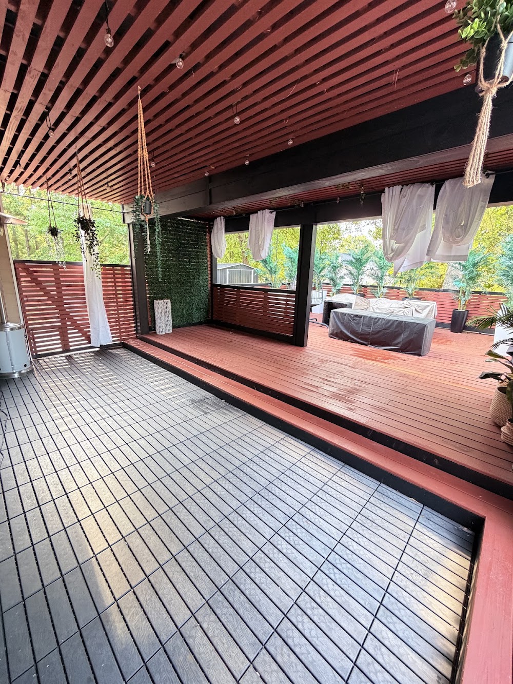Covered pergola with white drapes and greenery walls in daylight