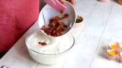 Cho lần lượt thịt xông khói đã nguội, phô mai bột và hành lá cắt nhỏ vào tô trứng đánh bông.