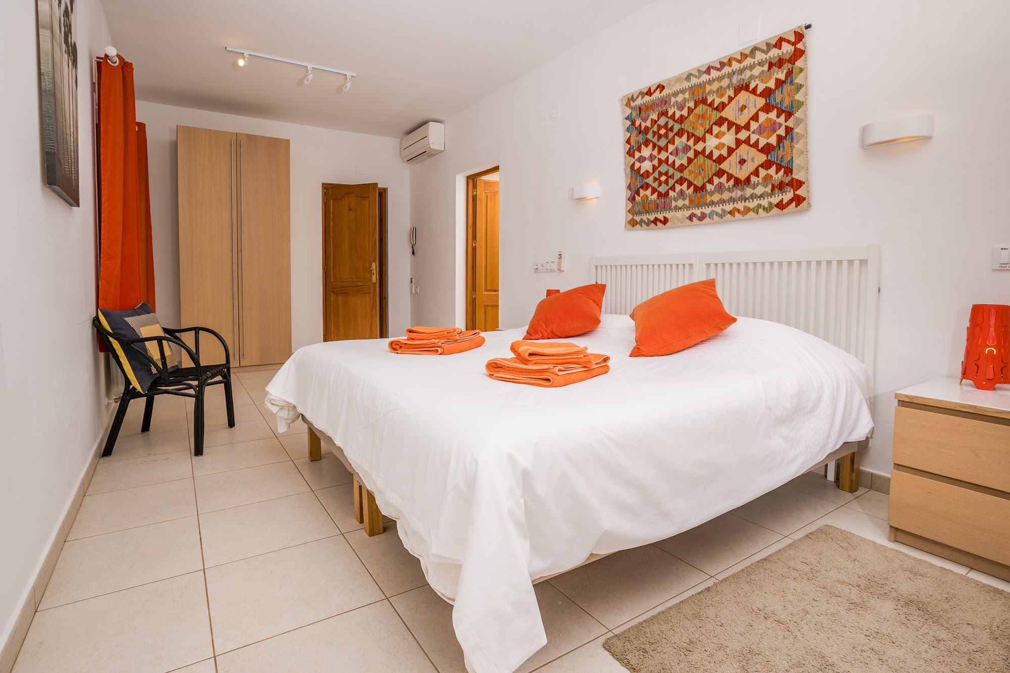 Double bedroom with crisp white linen and orange accents