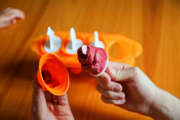 Manos sosteniendo un helado de los moldes para paletas de hielo Tovolo Dino