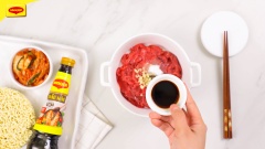 Thịt bò phi lê cắt thành miếng mỏng vừa ăn. Cho thịt bò vào tô, thêm vào 10gr tỏi băm, ½ muỗng cà phê tiêu, 1 muỗng cà phê đường, 1 muỗng cà phê dầu ăn, 1 muỗng cà phê nước tương Maggi, 2 muỗng cà phê dầu hào Maggi rồi trộn đều ướp trong 10 phút.