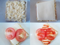 Cho bánh mì sandwich ra đĩa. Múc hỗn hợp trứng gà vào, thêm 1 miếng phô mai, cà chua cắt mỏng và tương cà lên trên.