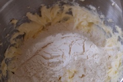 Rây bột mì và bột nở qua khay để loại bỏ vón cục. Trong 1 thố sạch, Đánh bơ và đường cho có màu vàng nhạt. Sau đó cho bột vừa ray vào, trộn cho quyện đều. Sau đó cho vào túi bóp kem.