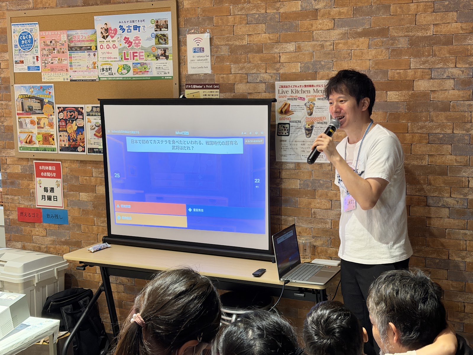 カステラのオリジナルクイズに参加する来場者と問題画面