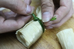 Khi đã cuốn xong thì dùng lá hẹ cột chặt từng cuộn tàu hũ ky để chả giò không bị bung ra khi chiên.