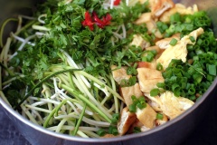 Bí ngòi bào sợi dài. Đậu hũ chiên thái khối vuông nhỏ. 2 quả trứng chiên lên, thái sợi. Ngò rí, hành lá rửa sạch, thái nhỏ. Đậu phộng rang giã dập. Giá đỗ rửa sach. Cho tất cả các nguyên liệu đó vào tô.