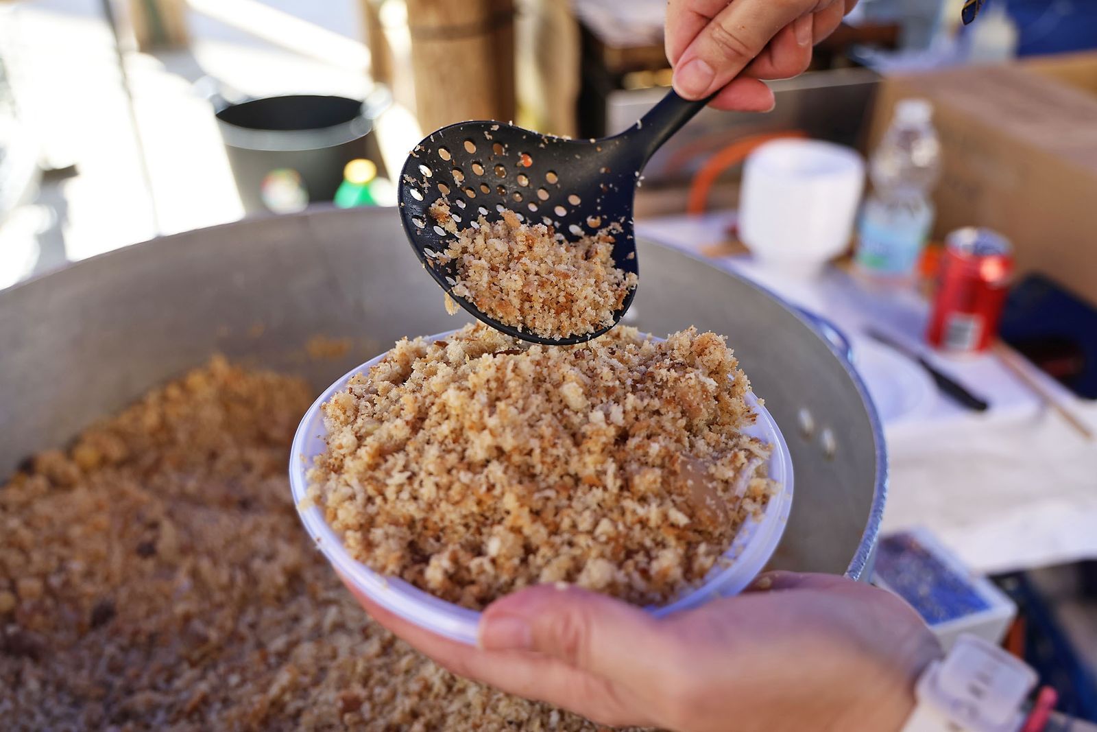 Freshly cooked migas being scooped from a large pan during an autumn food festival in Huelva.