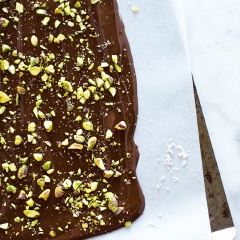 Hạt dẻ cười giã giập. Chocolate bạn cho vào nồi hấp cách thủy cho đến khi tan chảy. Chuẩn bị 1 cái khay rộng có lót sẵn giấy sáp hoặc giấy nến. Dùng dao phết trải đều chocolate ra, nhân lúc chocolate còn ấm, bạn nhanh tay rải hạt dẻ cười lên mặt chocolate.