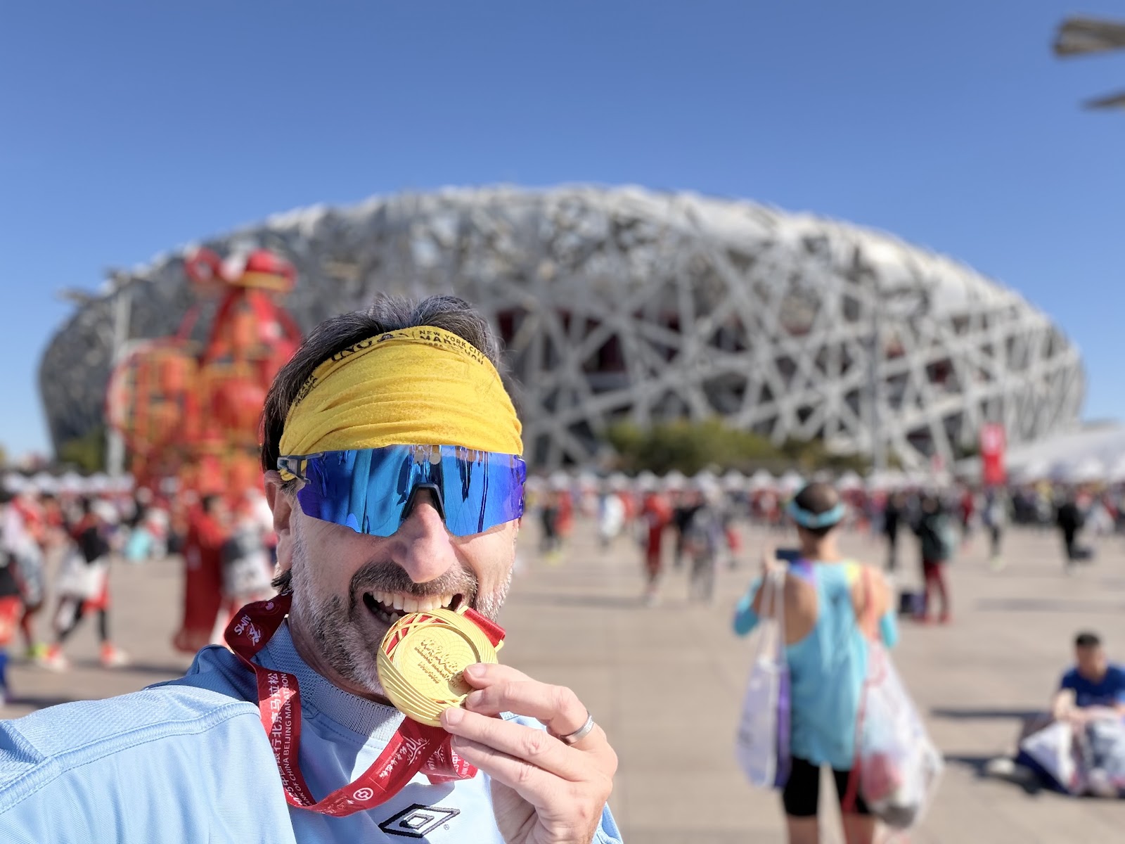 Kavarkes con la medalla de la Beijing Marathon frente al Nido de Pájaro