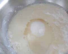Trộn bột với 7gr men nở, 3 quả trứng gà, 4 muỗng canh đường, 1 muỗng canh muối rồi cho khoảng 100ml sữa bơ vào trộn đều. Tiếp tục cho chỗ sữa bơ còn lại vào thật từ từ, vừa cho vừa trộn đều. Nhào bột tới khi thành hỗn hợp mịn, dẻo quánh, nếu bị khô quá thì có thể cho thêm chút nước ấm và nhào.