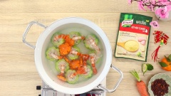 Đun sôi 1.2 lít nước, sau đó nhẹ nhàng thả từng khoanh khổ qua tôm xòe vào nồi, cho thêm 80gr cà rốt cắt lát tỉa hoa vào rồi nấu thêm 20 phút. Khi khổ qua và cà rốt chín mềm thì nêm vào 1 muỗng canh Bột nêm tự nhiên vị gà Knorr, khuấy đều rồi tắt bếp.