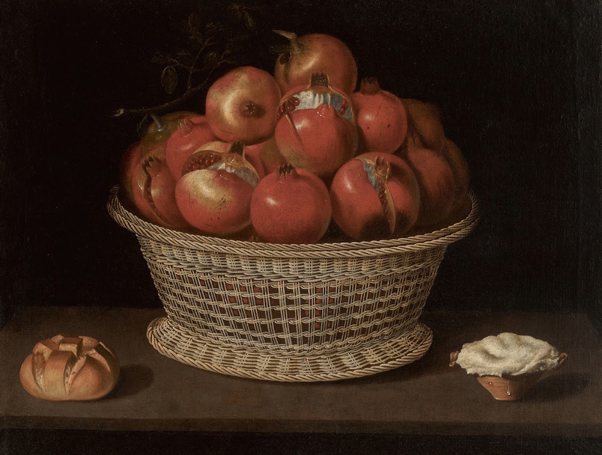 Still life of pomegranates in a basket a bread roll and a pastry on a ledge