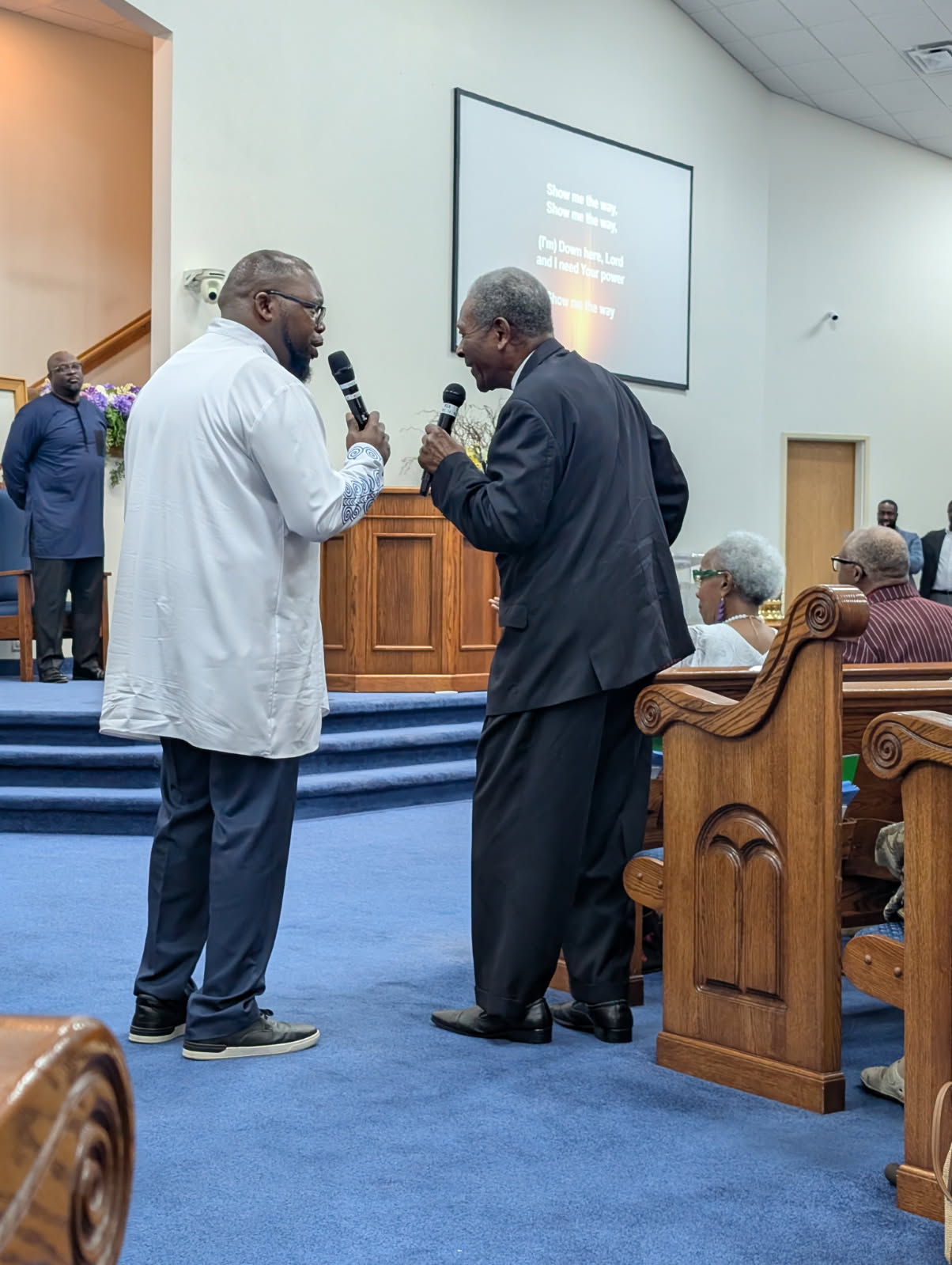 Two ministers sharing the microphone during Homecoming 2026 worship service at Sharpe Road Church of Christ