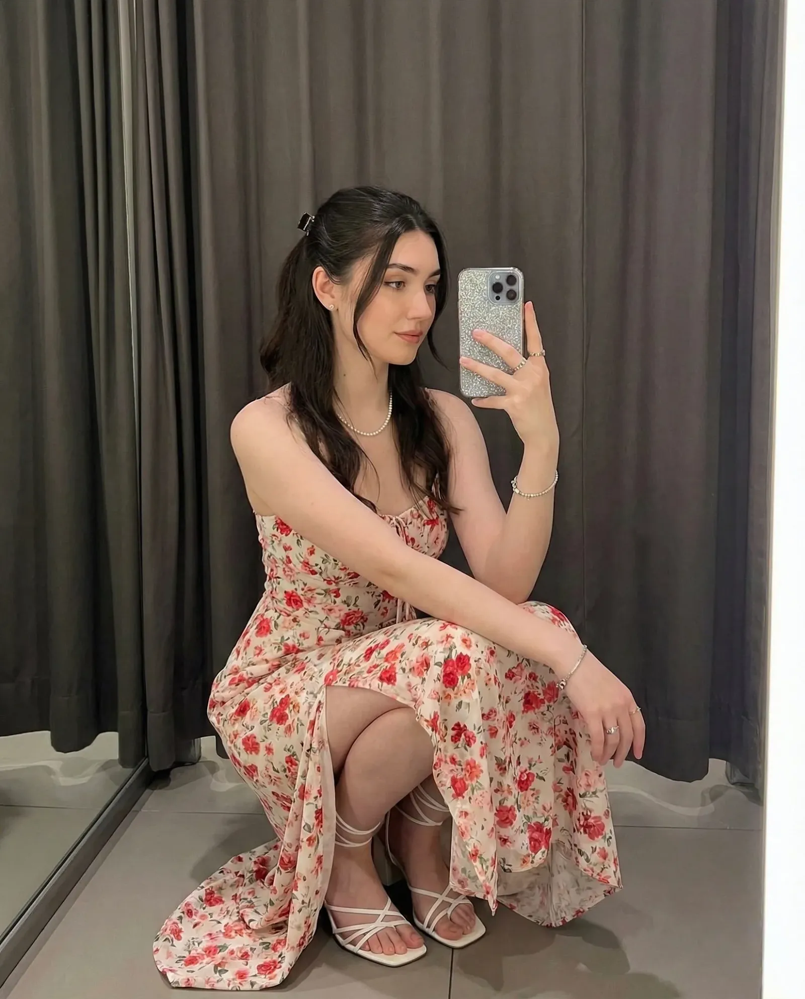 Imagen elegante de una joven en cuclillas tomándose una selfie en interiores.