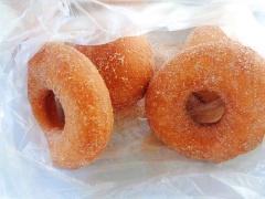 Khi bánh donuts custard chiên đã nguội và rút hết dầu thì cho bánh vào túi nilon, thêm 100g đường, 1 muỗng cà phê bột quế rồi xóc đều.