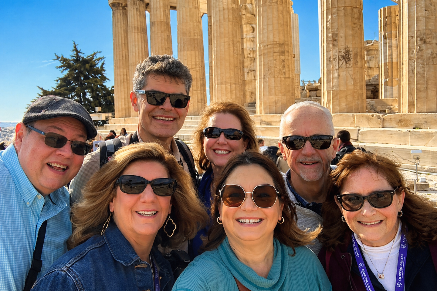 Group of friends smiling at the Acropolis in Athens Greece wearing sunglasses during a group travel cruise
