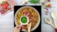 Thêm cơm trắng vào chảo, chiên cho cơm và các loại rau củ sao cho trộn đều vào nhau, cơm áo màu vàng đẹp từ kim chi. Nêm nếm với 1 muỗng canh nước tương, 1 muỗng canh dầu mè là vừa ăn. Thêm thịt xông khói, hành lá cắt nhỏ vào, đảo đều rồi nhắc xuống.