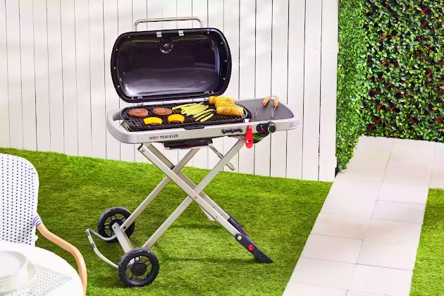 Barbecue à gaz portable Weber Traveler avec des aliments grillés dans le jardin