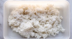 Nấu cơm chín, múc cơm ra thố chữ nhật, xới cho cơm tơi hơn và nhanh nguội. Thêm vào cơm 2.5 muỗng giấm gạo, 1 muỗng đường, 3/4 muỗng muối rồi trộn thật đều lên cho gia vị thấm vào cơm. Gọt vỏ dưa leo và bơ, cắt phần thịt trái bơ cùng dưa leo thành các sợi dài vừa ăn. Lột bỏ lớp vỏ bọc bên ngoài thanh cua, cắt miếng dài. Trộn 2 muỗng sốt mayonnaise, 2 muỗng tương ớt và 1 chút ớt bột vào chén, khuấy đều lên. Chuẩn bị sẵn mè và rong biển để cuộn.