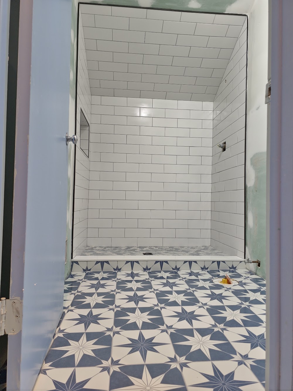 Walk in shower with white subway tile and blue star floor tile in Chester NJ