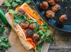 Sau đó, rạch các miếng bánh mì ra, lần lượt phết hỗn hợp mayonnaise và tương ớt vào bên trong rồi cho dưa chua, thịt viên chiên, ớt cắt lát và ngò rí rồi thưởng thức nhé!