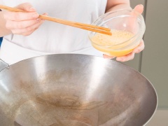 Hành lá rửa sạch, thái nhỏ. Cà rốt gọt vỏ, rửa sạch, thái hạt lựu nhỏ. Về phần cơm, cơm chiên ngon nhất là khi dùng cơm nguội, nếu cơm của bạn còn nóng thì để nguội rối hãy chiên nhé. Đánh tan trứng gà. Bắc chảo lên bếp, cho dầu ăn vào đun nóng. Tráng 1 lớp trứng gà vào chảo.