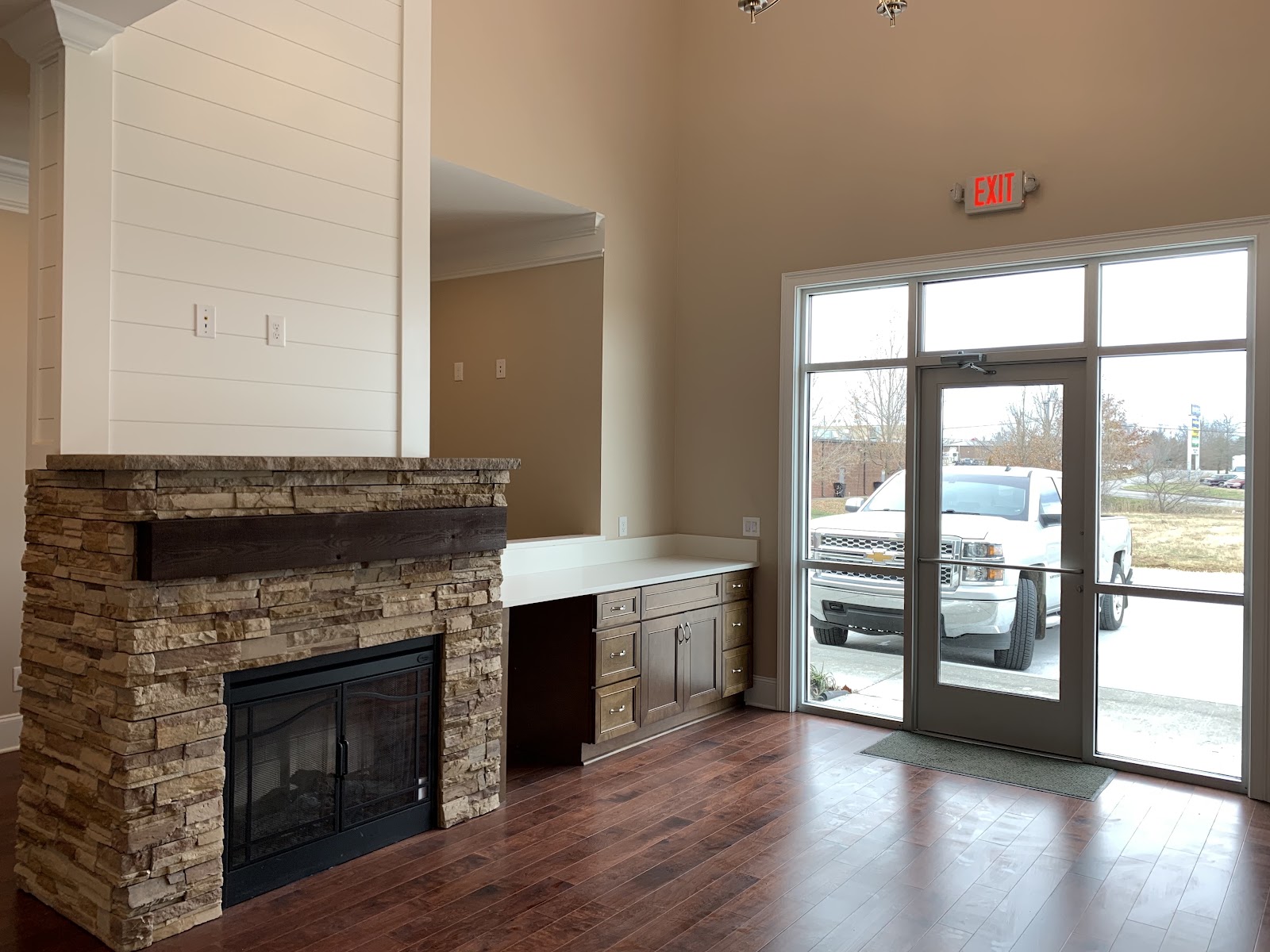 Interior room of the health clinic featuring a stone-veneer fireplace, dark wood floors, and a built-in cabinet near a glass exit door.