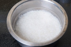 Tỏi bóc vỏ, băm nhuyễn. Vo sạch gạo và ngâm với nước khoảng 20-25 phút, sau đó vớt ra để ráo. Bắc chảo dầu olive lên bếp, cho tỏi băm vào phi thơm, sau đó cho gạo vào đảo đều.