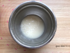 Khuấy đều 250ml nước ấm và 6g men trong một thố lớn. Khuấy đều tay cho men tan vào trong nước. Sau đó rây vào 500g bột mì, 100g bột gạo lứt mè đen, trộn đều. Sau đó đập 2 quả trứng vào thố bột, dùng tay nhồi bột bánh bao cho thành khối đồng nhất.