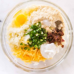 Bật lò trước ở 400 độ F. Bông cải rửa sạch nhiều lần với nước muối, tách nhỏ, luộc hoặc hấp chín, sau đó xay nhuyễn và vắt kiệt nước. Thịt xông khói áp chảo và thái nhỏ. Ướp bông cải với muối, tiêu, trứng gà, phô mai, bột tỏi, bột hạnh nhân, sữa chua, thịt xông khói, hành lá băm.