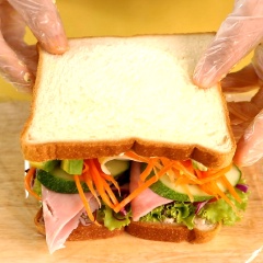 Sau đó, lấy 1 miếng sandwich khác phết lên trên 1 lớp sốt mayo và mù tạc vàng đã chuẩn bị sẵn ở bước trên, rồi 1 lớp trứng khuấy. Rồi đậy miếng sandwich đã có sẵn nguyên liệu lại, rồi dùng màng bọc thực phải bọc lại, bọc bên ngoài lớp giấy nến sao cho khối bánh hình vuông và chắc chắn.