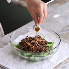Vẫn chảo đó, thêm 1 muỗng canh dầu ăn vào, đun nóng, cho thịt bò ướp, nấm và ớt vào xào cho thịt bò chín thì vớt ra. Cho bò xào vào tô dưa leo, thêm 1/2 muỗng canh dầu ô liu và mè trắng rang, trộn đều lên là có thể dùng.