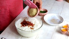 Cho lần lượt thịt xông khói đã nguội, phô mai bột và hành lá cắt nhỏ vào tô trứng đánh bông.