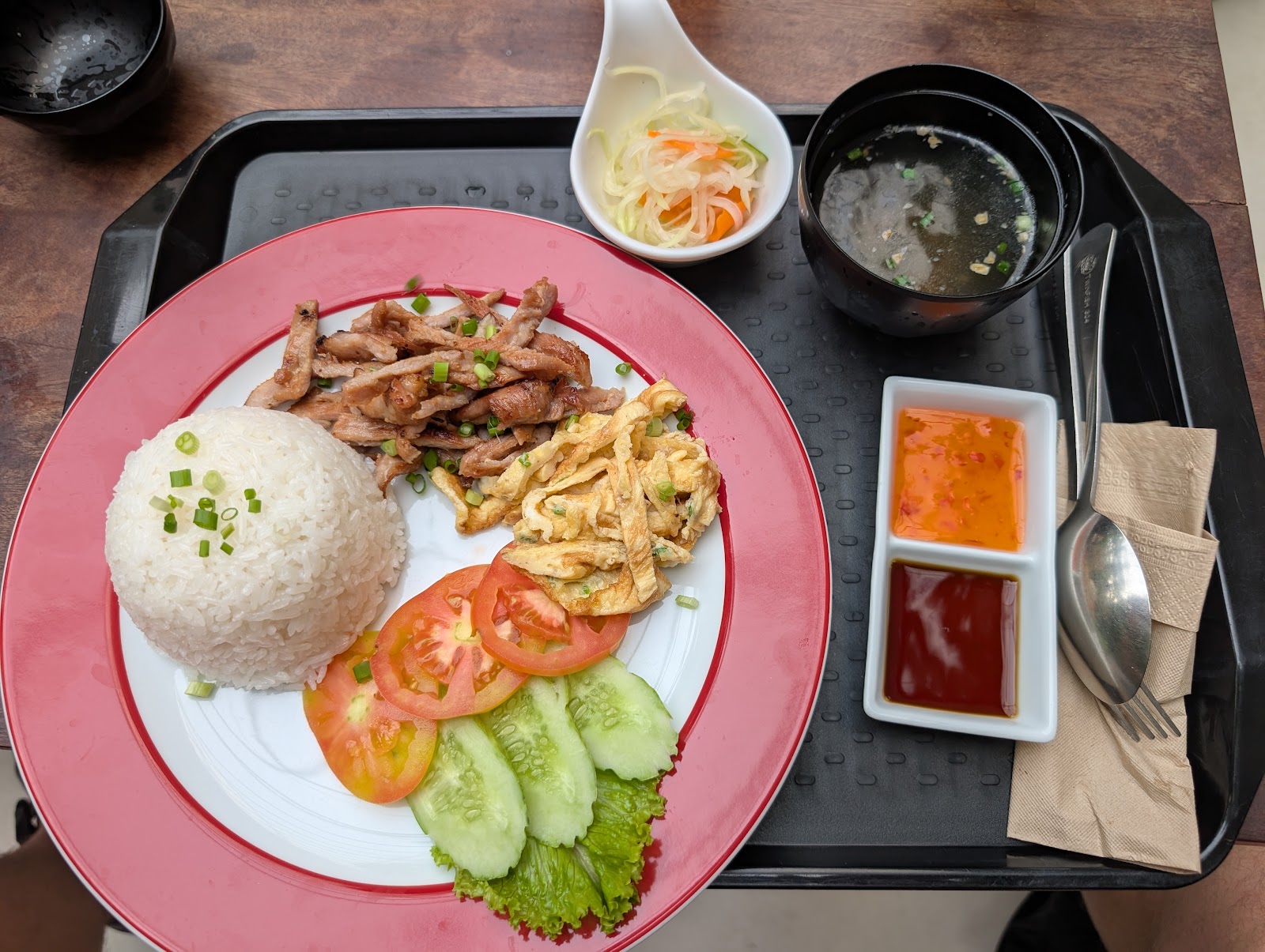 A breakfast of 'bai sach chrouk' which is pork and rice.
                 Served with tomatoes, cucumbers, some pickled veggies, a cut
                 up omelet, a couple different sauces on the side,
                 and a miso-like soup.