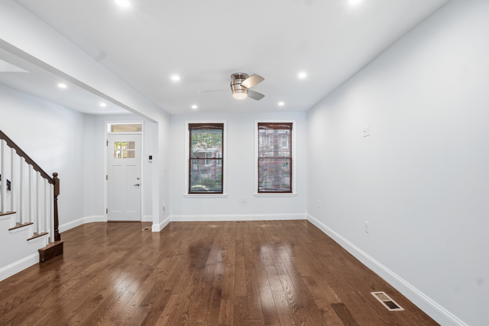 Freshly renovated open-plan living area with hardwood floors, bright white walls, recessed lighting, and front entry — whole-home renovation by HousePro