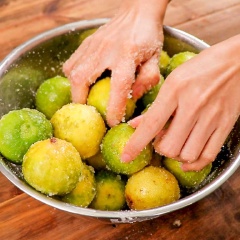 Chà 1.5kg chanh giấy rửa sạch cùng 200gr muối hột cho đến khi muối chuyển sang màu xanh, đem rửa sạch.