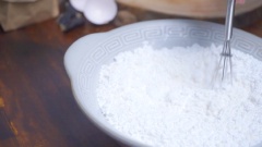 Làm vỏ bánh gối nhân thịt: Trộn 250gr bột mì, 50gr bột gạo, 1 muỗng cà phê muối và 1 muỗng cà phê đường lại với nhau cho đều. Thêm vào tô bột 2 quả trứng gà, trộn đều.