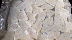 Cho khoai môn đã bào mỏng vào tô lớn, chế 1 muỗng xanh dầu ăn vào, dùng tay đã bao nilon trộn cho dầu bám thật đều vào từng lớp khoai. Lót một lớp giấy nhôm dùng để nướng lên khay nướng. Nhúng cọ vào dầu ăn, phết một lớp lên giấy nhôm. Xếp các lát khoai môn khay nướng và không để khoai chồng lên nhau nhé, mỗi miếng khoai là một vị trí.