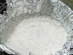 Lấy một chiếc xoong vừa đủ chứa con gà, sau đó dùng giấy bạc lót xoong. Làm như vậy để khi hấp sẽ không bị cháy xoong. Sau đó giải đều gói muối xuống dưới đáy xoong.