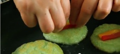 Lật bánh khi mặt dưới của bánh có màu vàng nâu. Dùng muỗng ấn 2 miếng ớt đỏ và vàng vào bánh để trang trí. Sau đó, chiên bánh trong 1 phút khi mặt dưới có màu vàng, tiếp tục lật bánh (mặt có ớt trang trí) và chiên thêm trong 10 giây là được. Tương tự như vậy với phần bột còn lại.