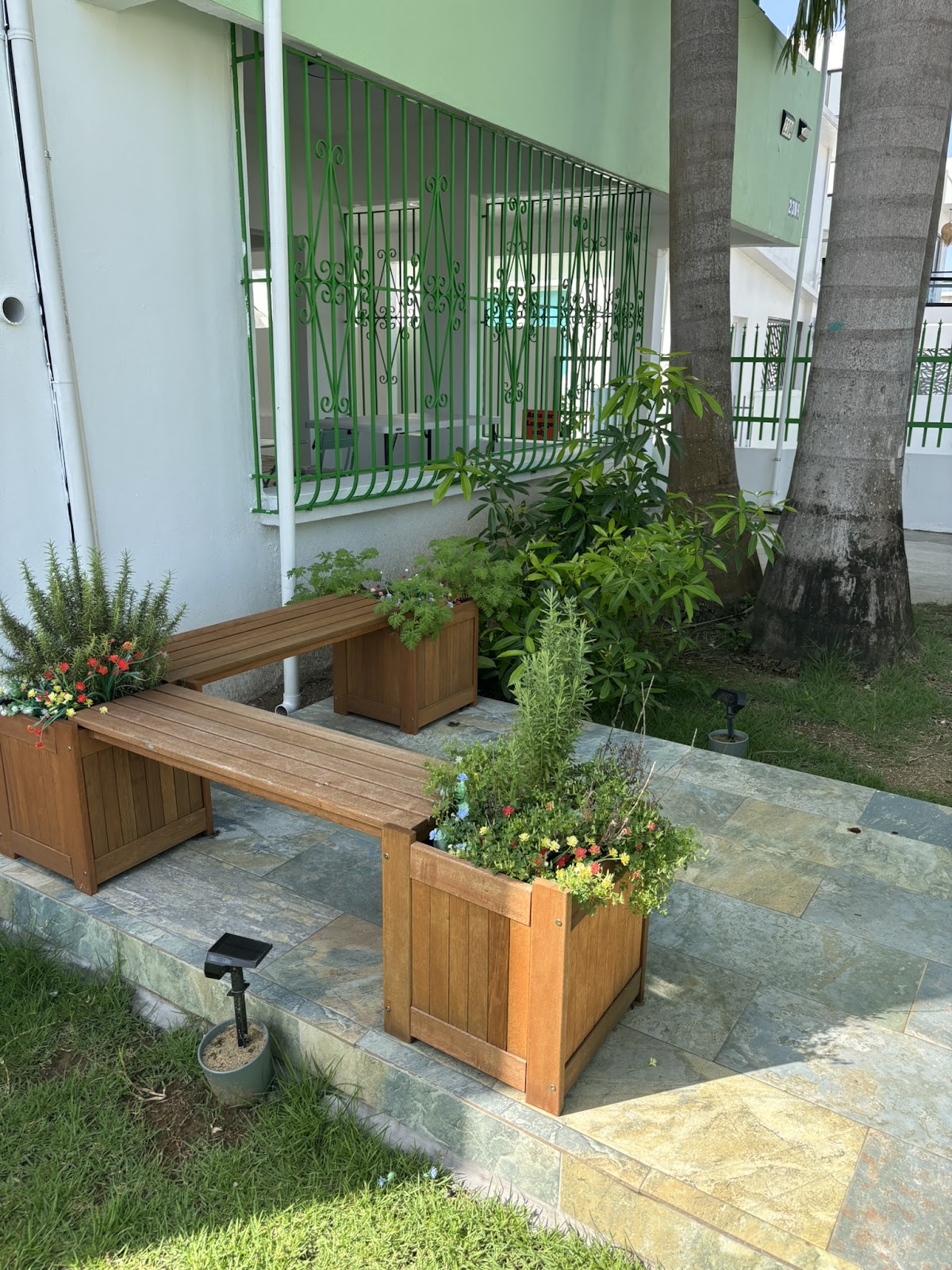 Apartment entrance with a bench and lush greenery