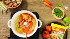 Bắc nồi lên bếp, cho vào 2 muỗng canh dầu ăn, chờ dầu nóng thì cho 50gr sả cây đập dập, 30gr riềng cắt lát đập dập, 5 trái ớt trái đập dập vào xào thơm. Sau đó cho thêm 100gr cà chua cắt múi cau và 100gr thơm cắt lát vào nồi, thêm 1/2 muỗng cà phê muối vào xào chung cho rau củ nhanh mềm để tạo màu đỏ đẹp mắt. Khi cà chua và thơm mềm thì chế vào nồi 1.5 lít nước lọc rồi đun sôi, hớt bỏ bọt dơ.