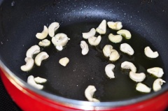 Đun nóng 2 muỗng canh dầu ăn, cho hạt điều vào rang cho hạt điều chín vàng và giòn thơm thì vớt ra để riêng. Tận dùng dầu còn dư trong chảo, thêm 3g hoa tiêu vào đun cho dậu mùi thơm rồi vớt bỏ tiêu.
