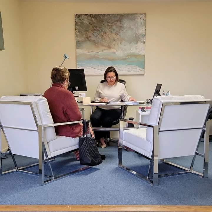 Claudia Azcunaga ayudando a preparar documentos migratorios en su escritorio