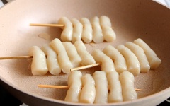 Sau khi đã chuẩn bị phần sốt, chúng ta sẽ áp chảo phần bánh gạo xiên que. Dùng que tre xiên qua từng bánh gạo, mình xiên mỗi que 5 bánh nên sẽ cắt ngắn khoảng 2/3 que xiên, còn ở nhà bạn có thể xiên mỗi que với số lượng bánh gạo tùy thích nhé. Bắc chảo với 1 muỗng canh dầu ăn, tráng dầu đều mặt chảo. Đợi đến khi dầu nóng bạn cho những xiên bánh gạo vào áp chảo. Đến khi mặt dưới vàng giòn thì trở mặt, làm tương tự với mặt còn lại. Gắp những xiên bánh gạo ra dĩa, phết lên một lớp sốt cay rồi rắc mè lên là hoàn tất.