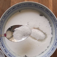 Sau đó đổ bột báng ra rổ lưới rồi xả dưới vòi nước lạnh cho bột báng không dính vào nhau. Rồi tráng bột báng qua nước lọc đun sôi 1 lần thì cho vào tô. Đổ nước cốt dừa vào. Tiếp theo cho đường và muối vào, khuấy đều lên cho tan hết.
