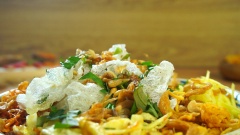 Cho bánh tráng ra đĩa, cho lần lượt khô gà, hành phi, tóp mỡ, rau răm và mỡ hành vào trộn cùng. Cuối cùng rắc hành phi và đậu phộng, rưới nước sốt me chua ngọt lên trên cùng là có thể thưởng thức món bánh tráng giòn tan hấp dẫn này rồi.