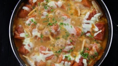 Cho phần phô mai mozzarella rắc đều lên mặt chảo xúc xích, đậy nắp chảo, để phô mai tan chảy đều cả mặt chảo thì rắc thêm 10gr hành lá cắt nhỏ lên. Tắt bếp, nhấc chảo xuống.
