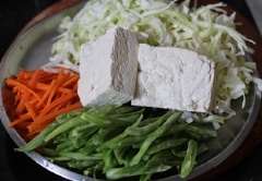 Cà rốt gọt vỏ cắt sợi, đậu que cắt lát và bắp cải cắt mỏng rửa sạch để ráo cùng đậu hũ. Bắc chảo lên bếp, nếu là đậu hũ trắng, bạn nên chiên sơ cho đều hai mặt đậu sau đó cho ra đĩa để ráo dầu.