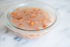 Hạnh nhân ngâm nước qua đêm rồi bỏ nước ngâm đi, để ráo. Vặn lò nướng ở nhiệt độ 350 độ F, trải hạnh nhân ra khay và nướng trong khoảng 10 phút cho tới khi hạnh nhân chuyển sang màu vàng nhẹ, bóng dầu là được.